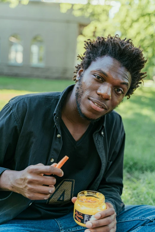 a young man holding a jar with an orange juice