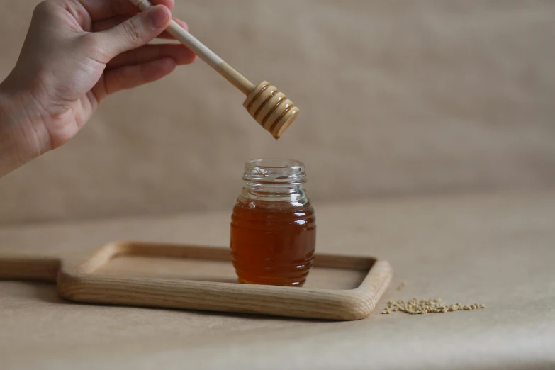 a person's hand is reaching into a honey jar