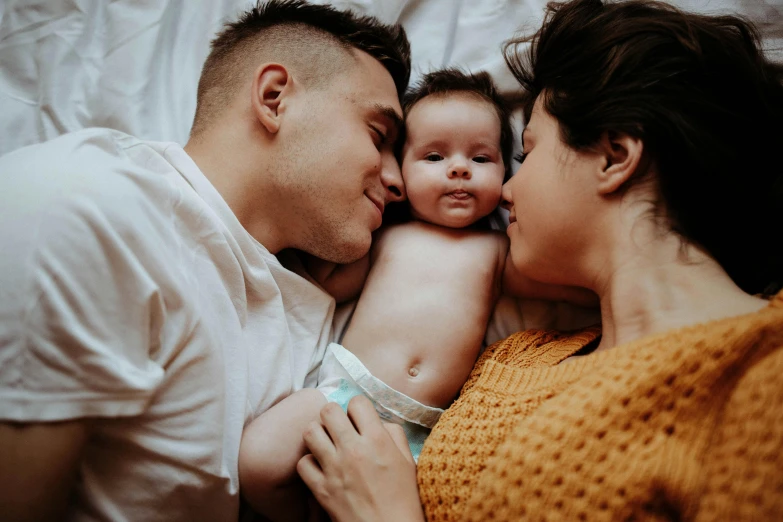 a couple is cuddling with a baby on the bed