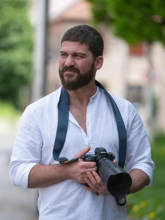 a man wearing a camera strap holding a camera