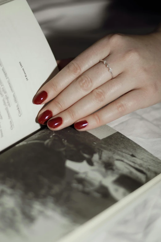 a woman with red nails holds up an open book