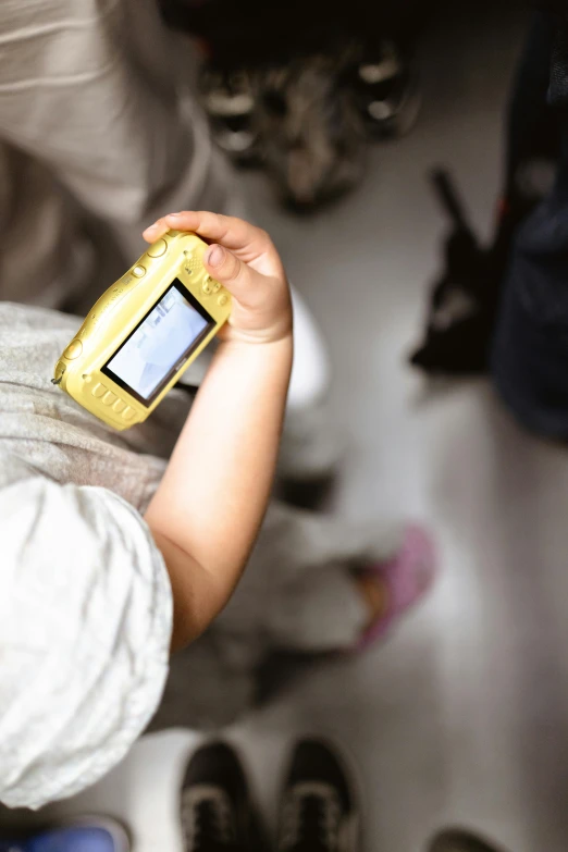 a child is holding a small cellphone with a cat nearby