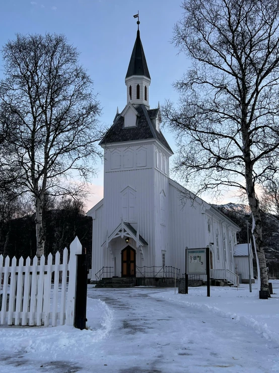 a white church with a steeple and gate