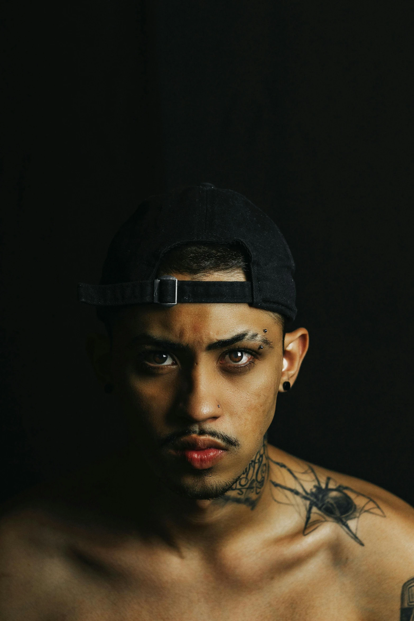 man with head tattoos and spider tattoo looking at the camera