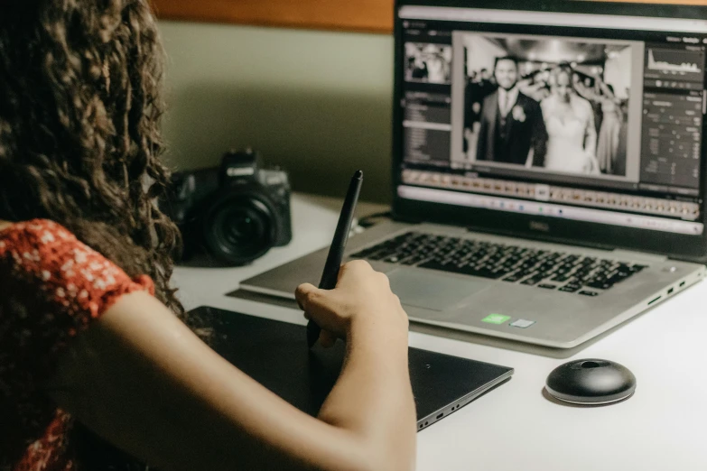 a woman is looking at a cell phone by a laptop