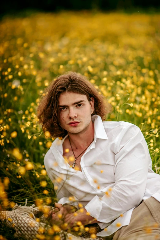 a man sitting in the grass with yellow flowers