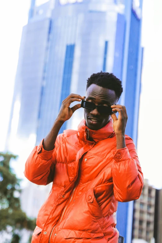 a black man in an orange jacket standing on the street