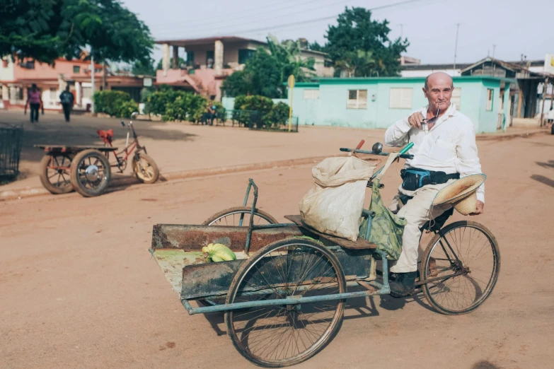 an elderly man rides an antique bicycle with a cart loaded with groceries