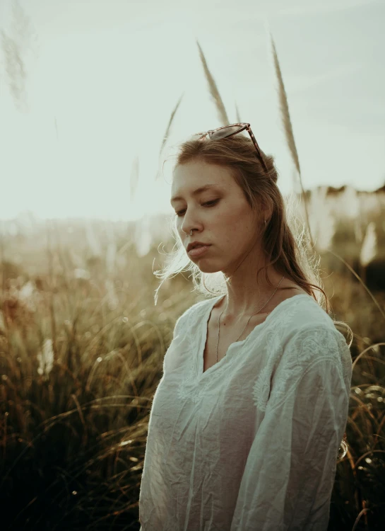 a woman with eyes closed standing in some tall grass