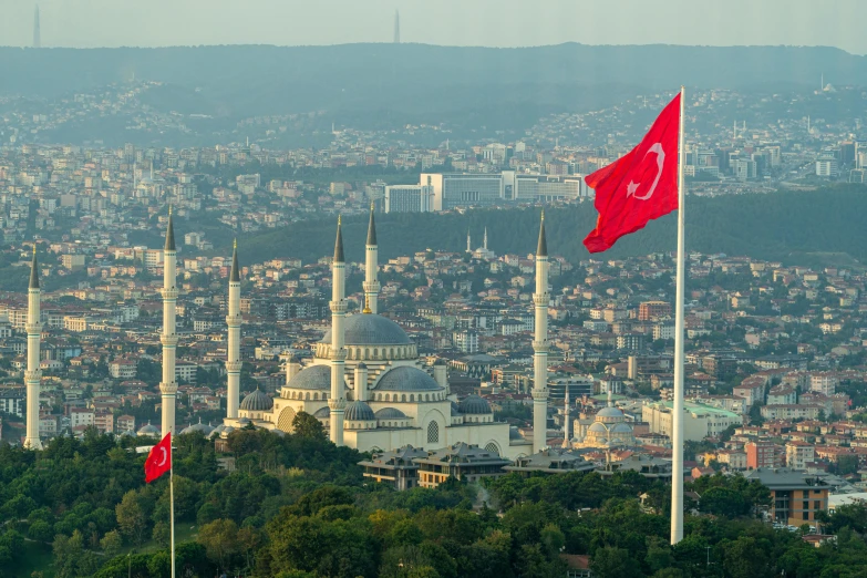 two flags flying in front of a cityscape