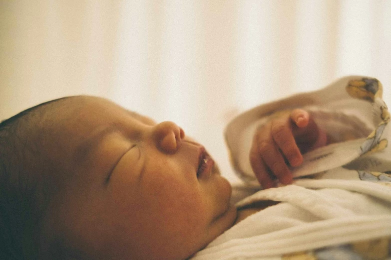 a baby is laying on a bed while clutching his hand