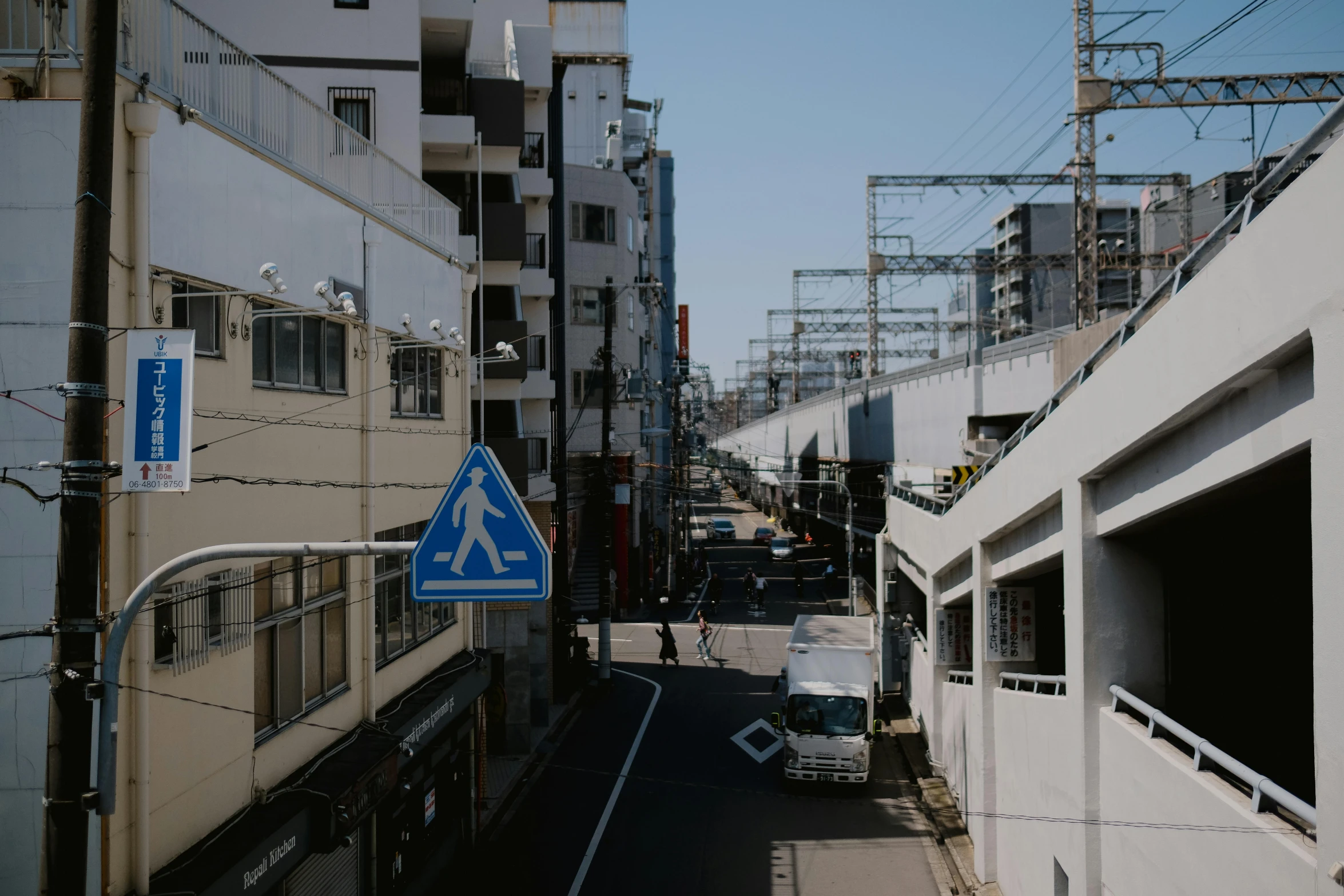 an empty city street with buildings, and a blue sign on it