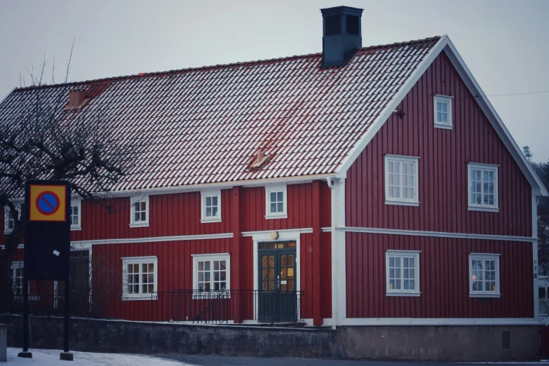 a building with a red roof has snow on the ground