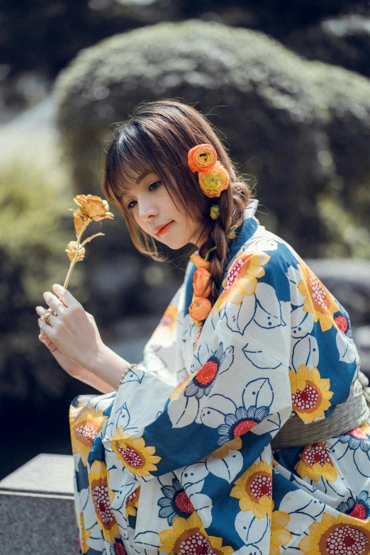 a woman with long hair in a kimono holding a flower