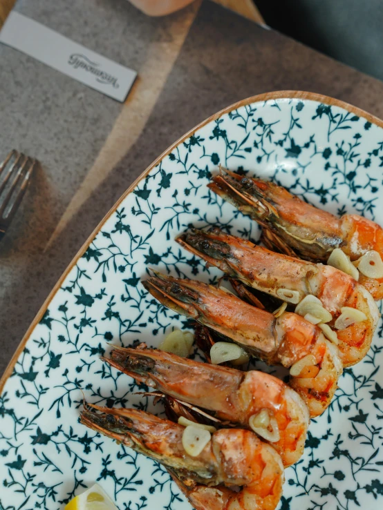 a serving dish with lobster, shrimp and lemon slices on it