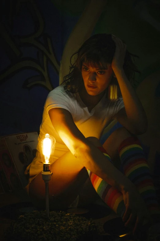 a woman sits and holds her hand to the side with a light on