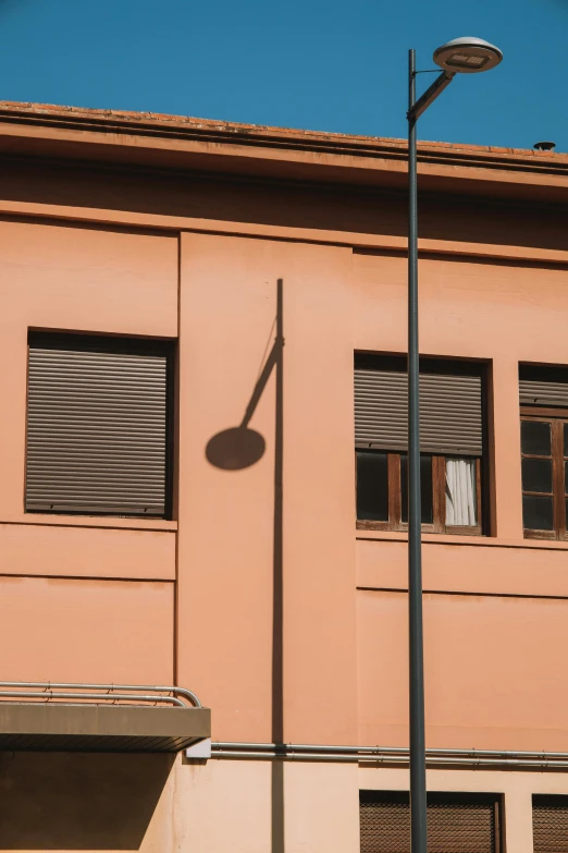 a street light sitting next to a tall pink building