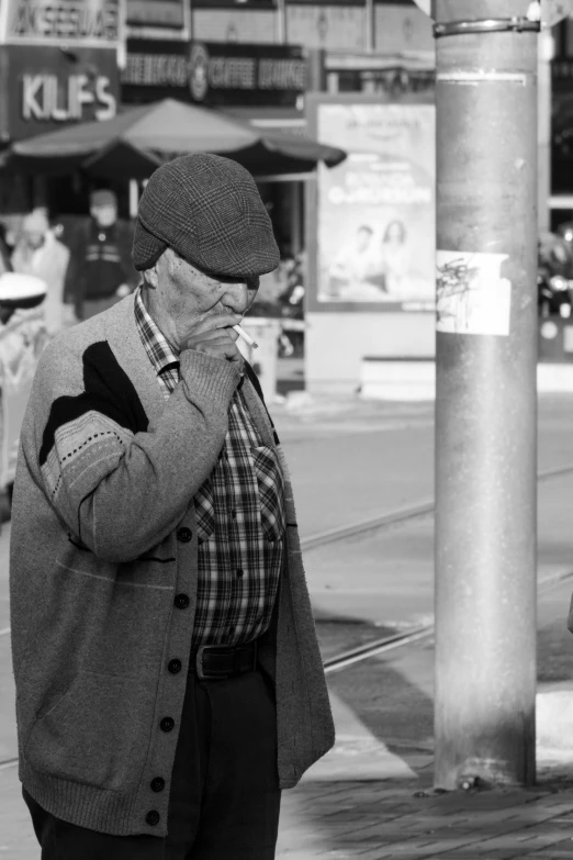 an old man smokes near a busy street