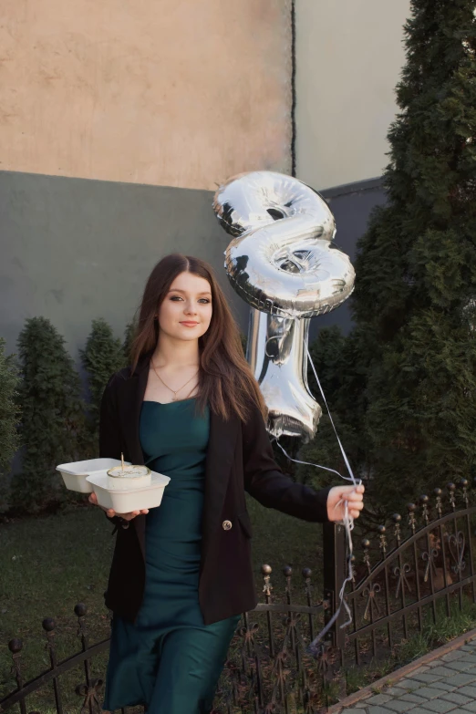 a woman wearing a suit holding up a balloon and some food