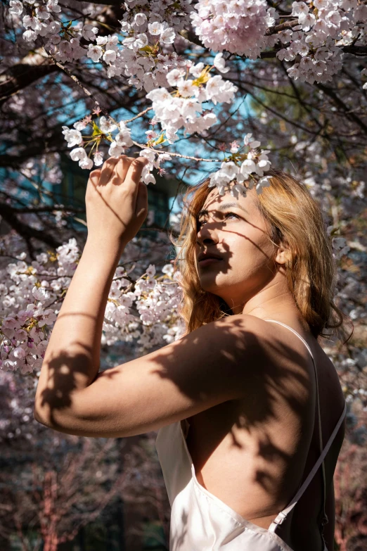 woman is wearing a white dress near blooming trees