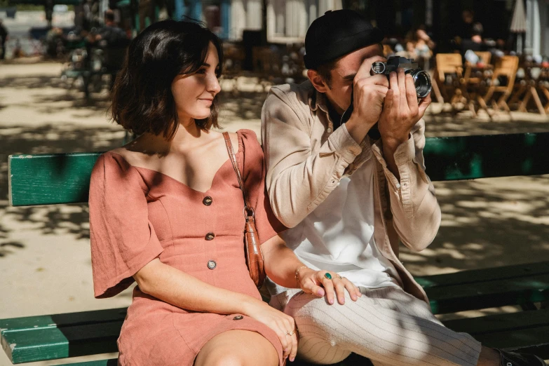 a young couple is sitting on a park bench and looking into the distance