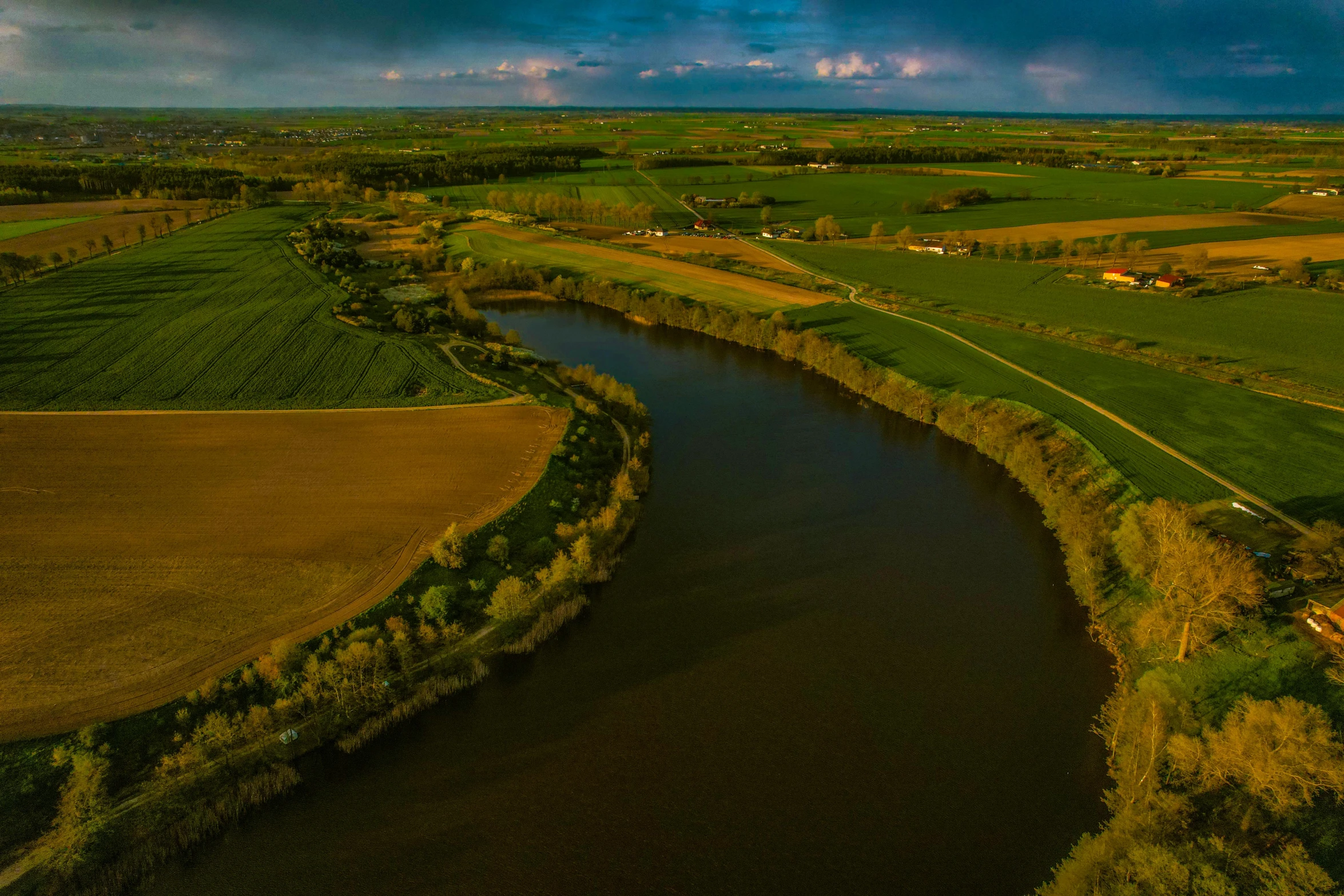 an aerial view of a river running through a green field