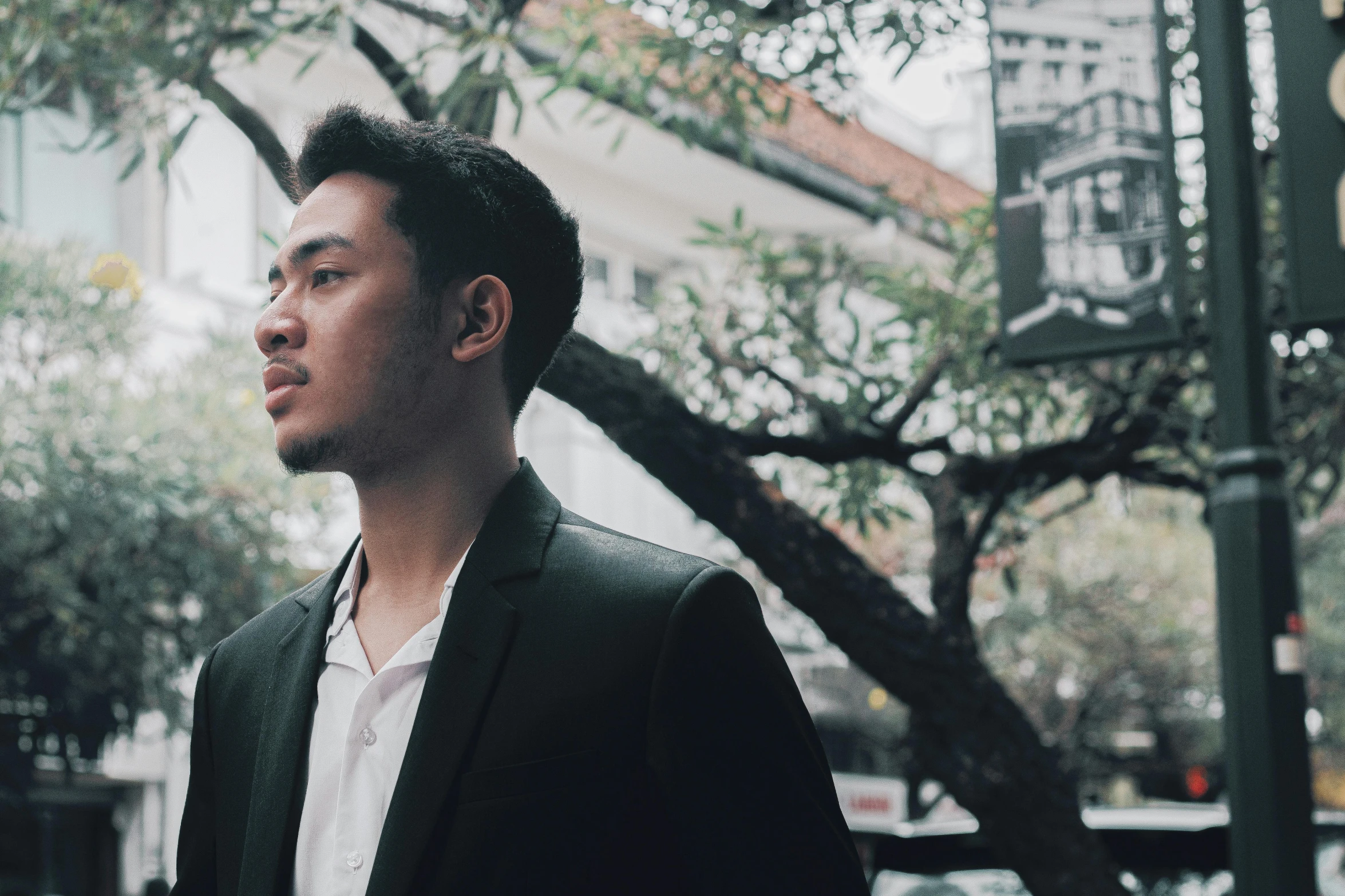 a man stands on a street corner in a black jacket and white shirt