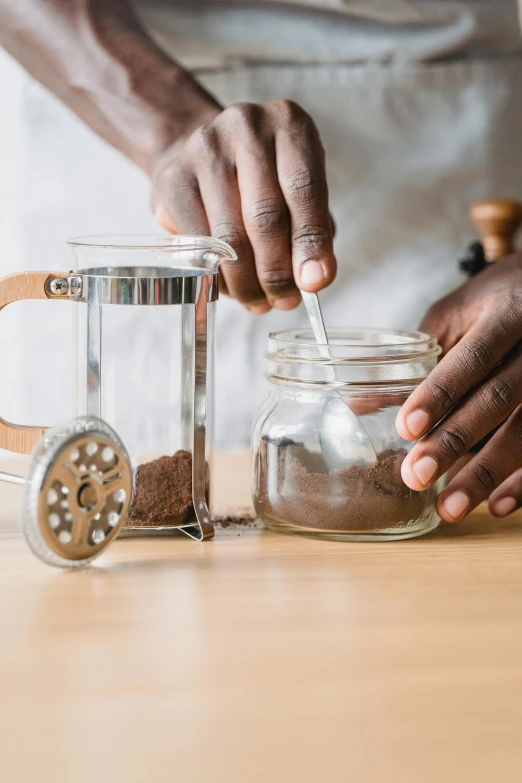 someone putting sand into a glass jar