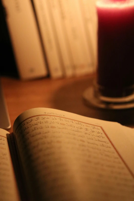 open book next to a candle sitting on a table