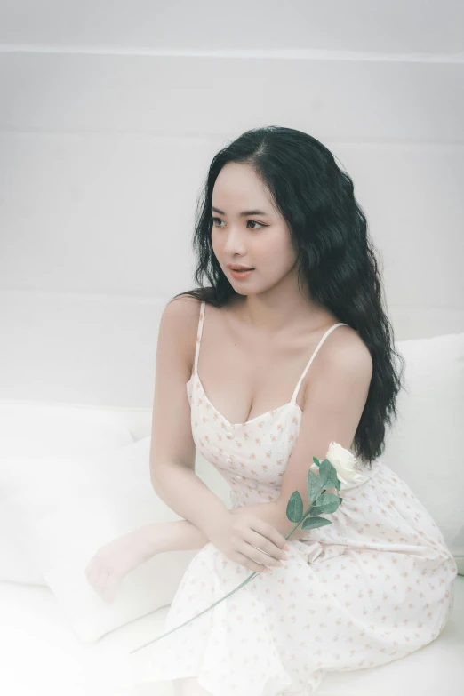 a pretty young asian woman in a white dress holding a flower