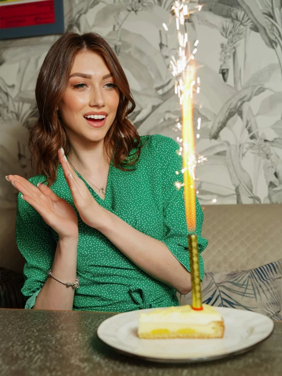 a woman standing in front of a cake holding a sparkler in her hands
