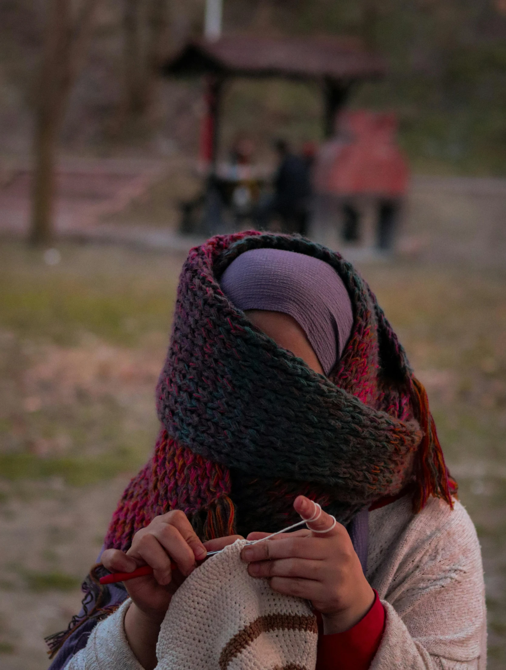 a person holds a crocheted hat on their head