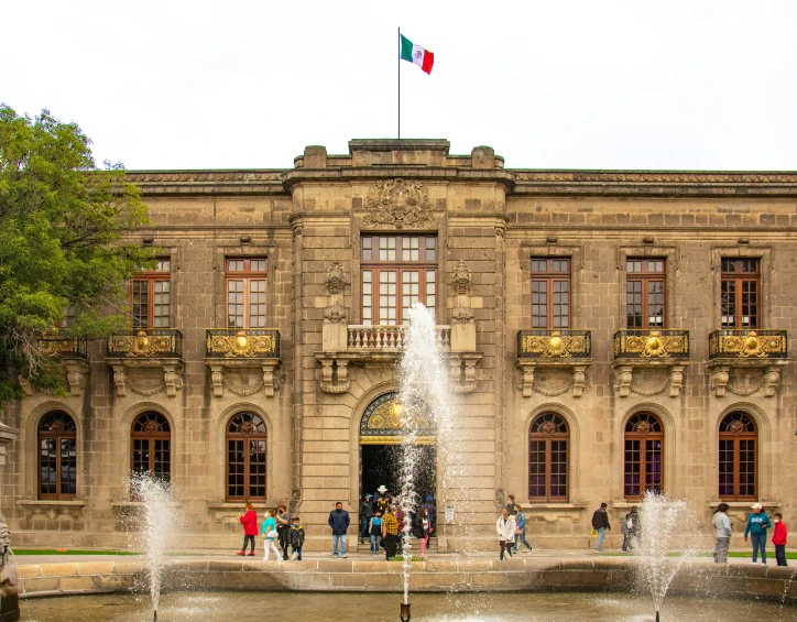 people walking in front of the water fountain in a plaza