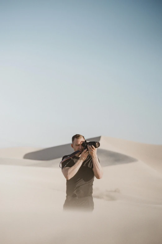 a person taking pictures with his camera in the sand