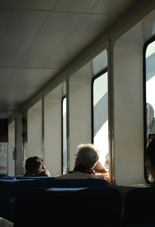 an older person looks out the window on a public train