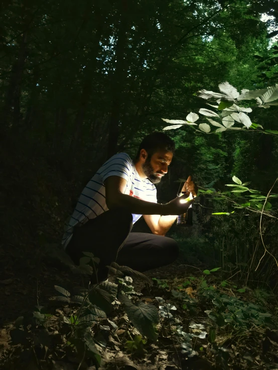 a man kneeling down and looking at a flashlight