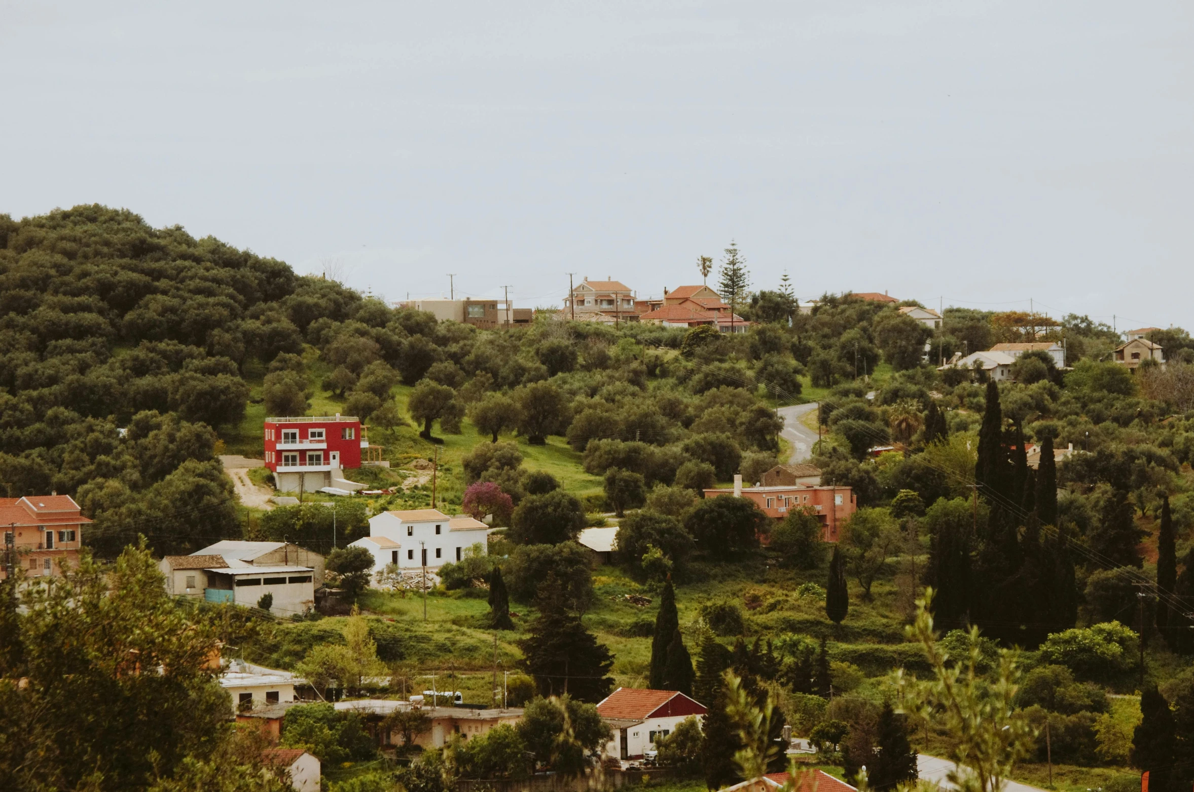 a small hillside with houses on it and green hills in the background