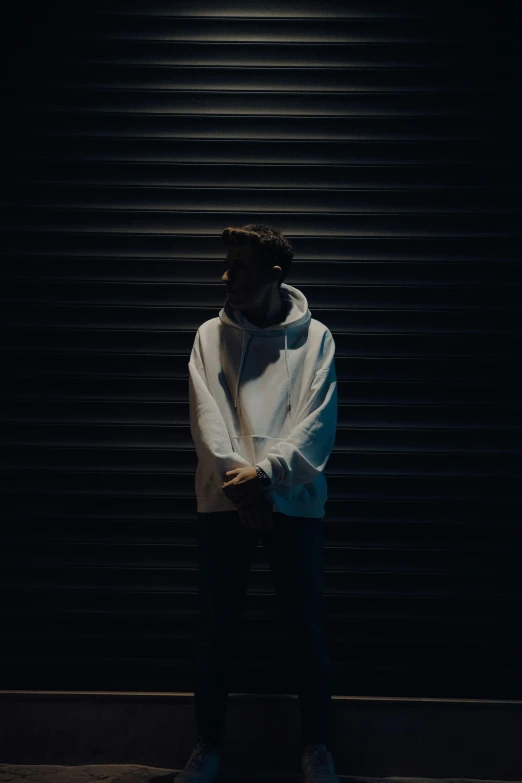 a man standing outside in the dark wearing a hoodie