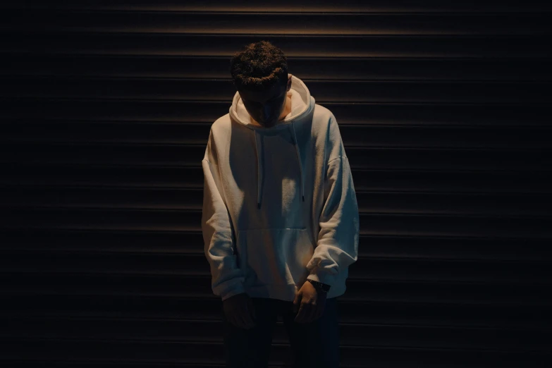 a man in a white hoodie and sweatpants in the dark