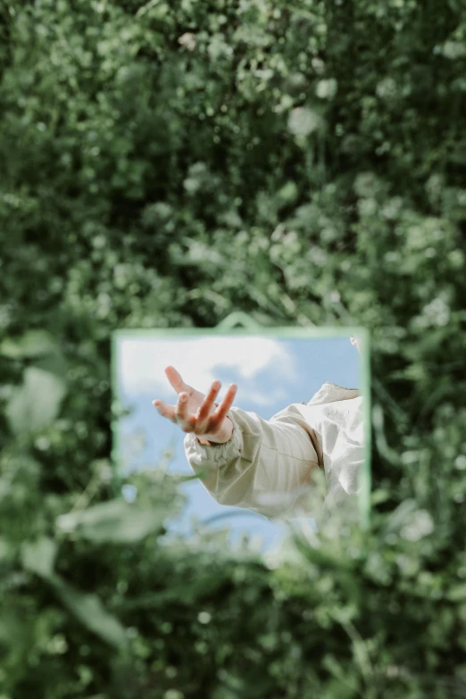 a person reaching into a mirror with their hand