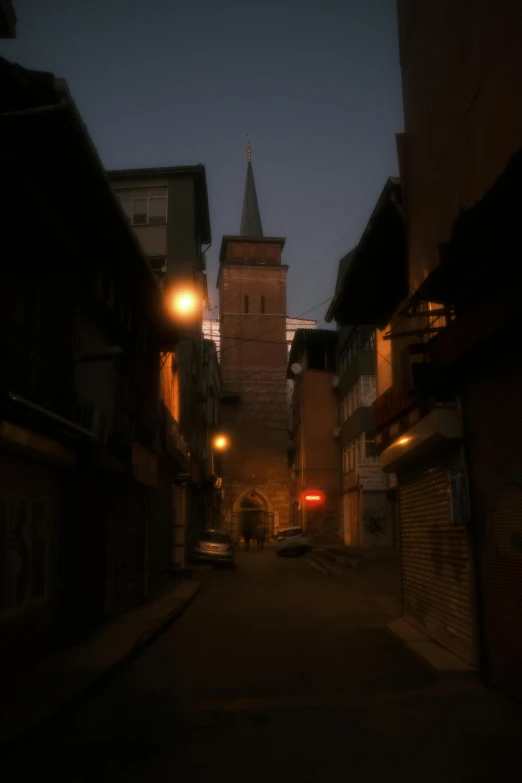 an old alley with a tall steeple and light shines at the end of it