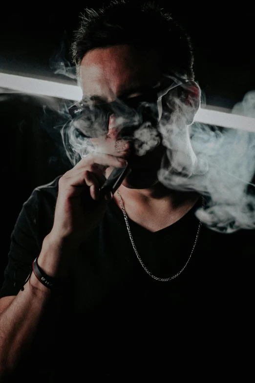 a man smoking in the dark with smoke in front of his face