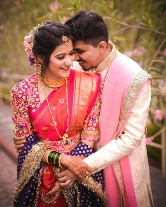 a couple emcing for a pograph in front of trees