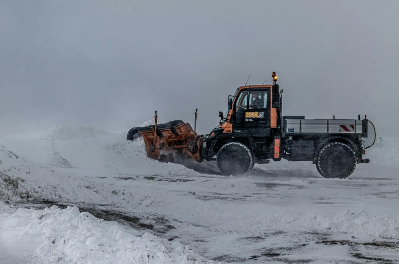 a snowplow pulling a tractor on a snowy road