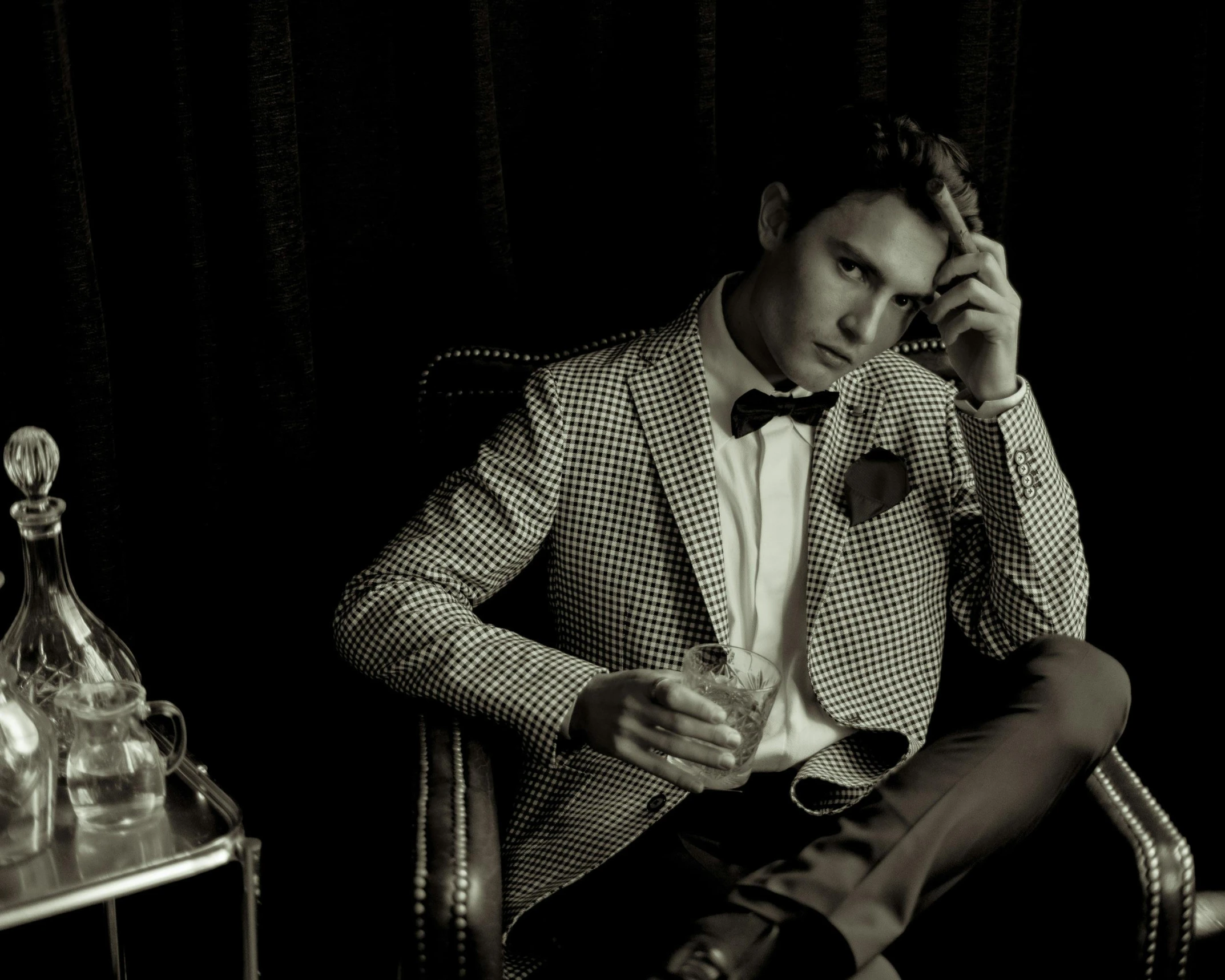 man sitting in chair in dark room with glass