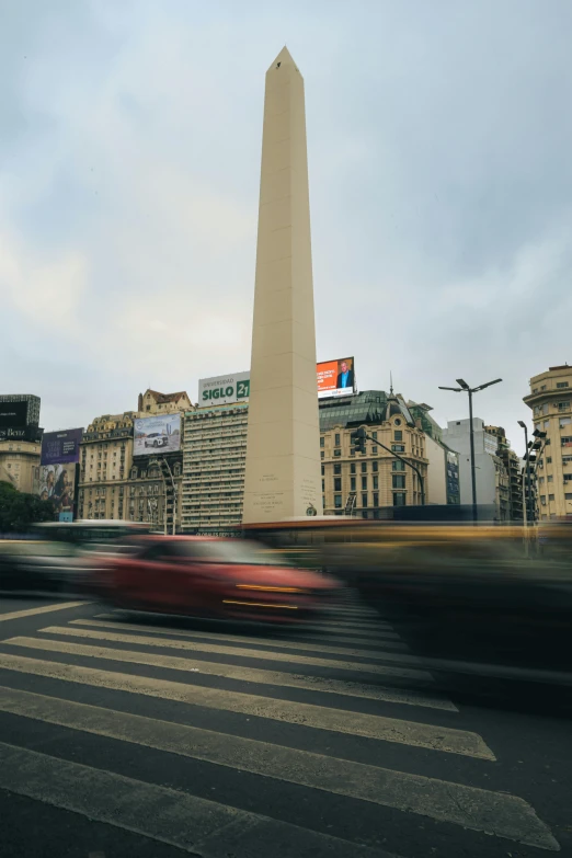 a view of a monument from a street, with buildings in the background