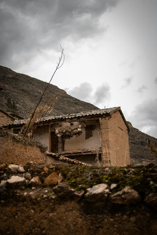 a dirt hut in the mountains on a cloudy day