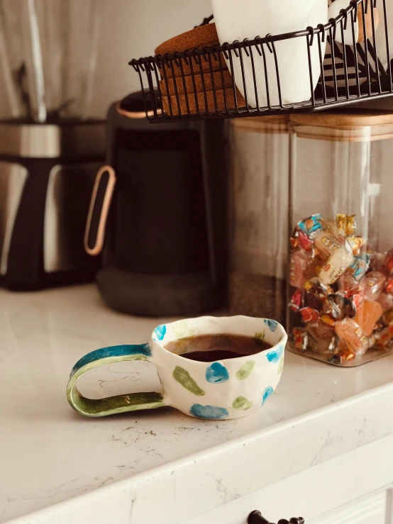 a coffee cup sits on a counter next to some cups