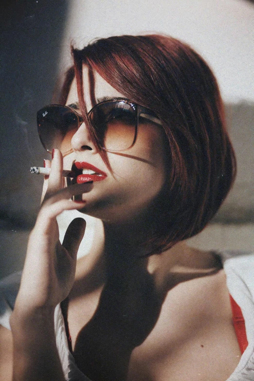 a young lady wearing dark sunglasses is smoking a cigarette