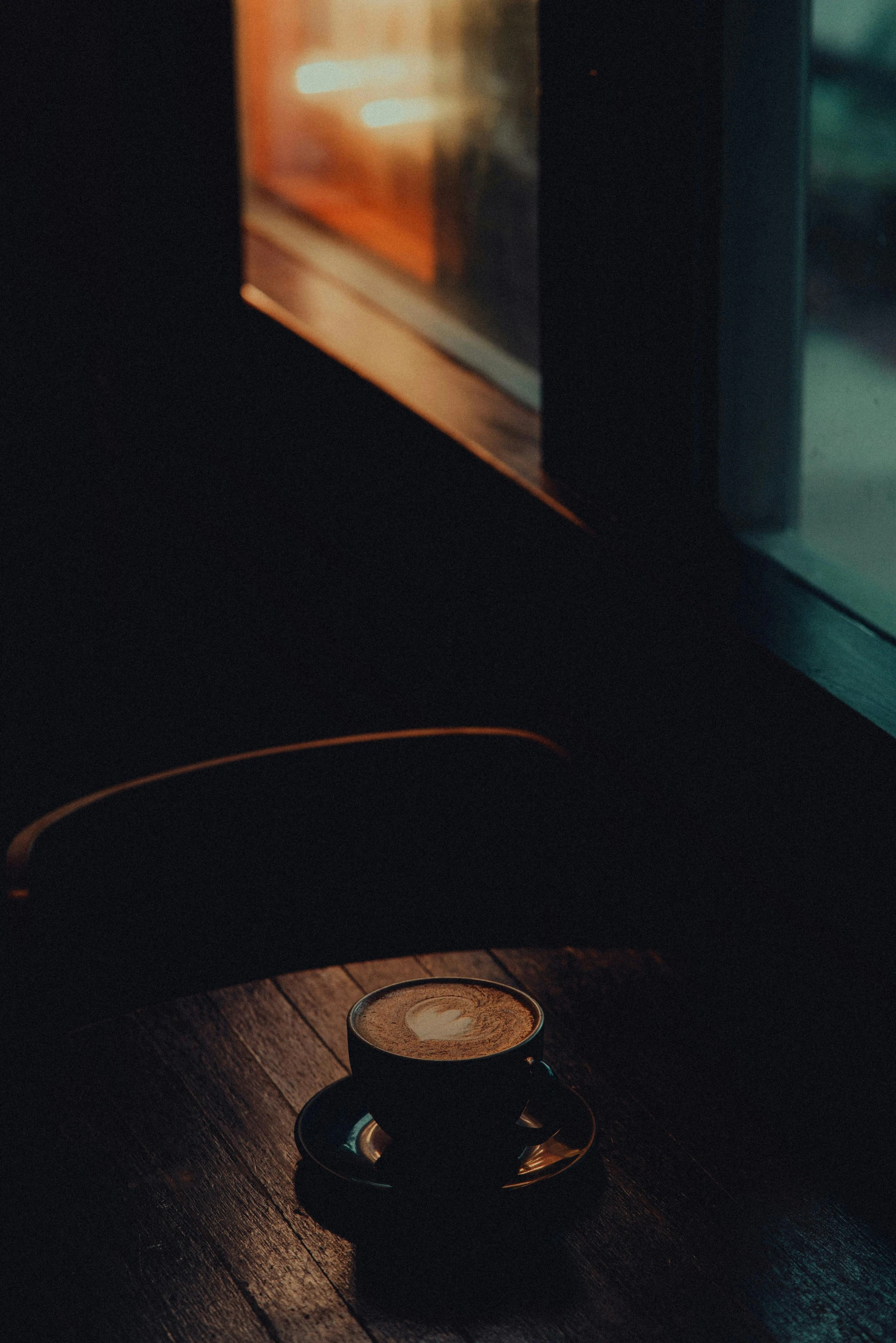a coffee cup sitting on a saucer in a darkened room